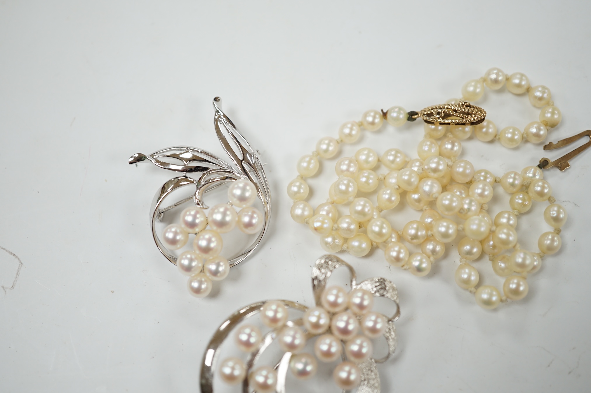 A Mikimoto white metal and cultured pearl cluster set spray brooch, 41mm, one other white metal and cultured pearl cluster set spray brooch, stamped 'silver' and a single strand cultured pearl necklace with a 9ct gold cl